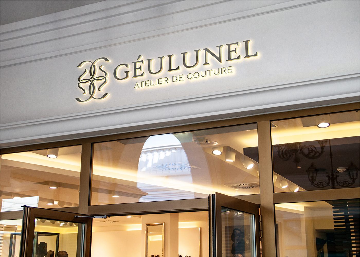 Géulunel illuminated logo sign above a couture boutique entrance
