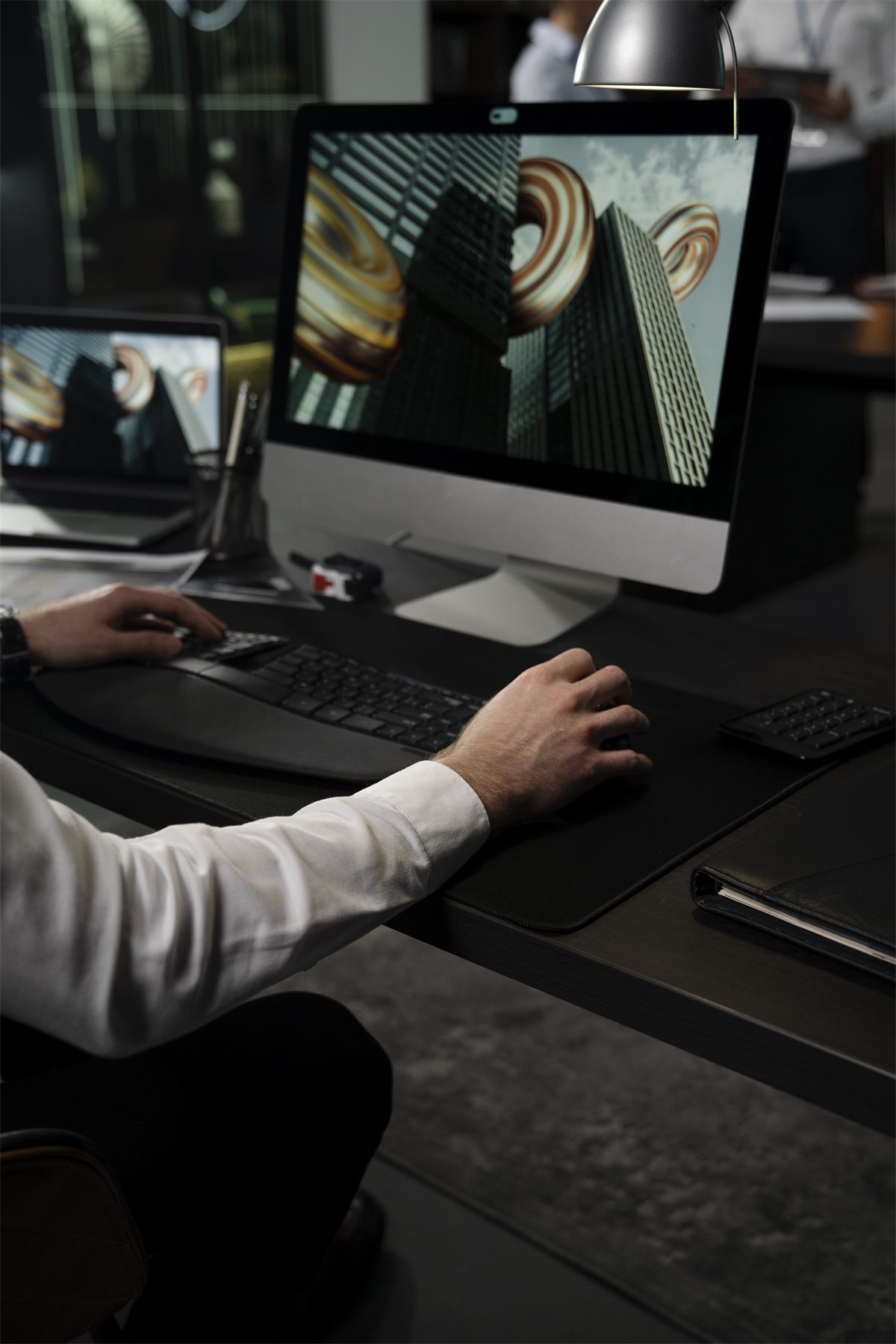 Designer working on a 3D artwork at a desktop computer in a dark studio